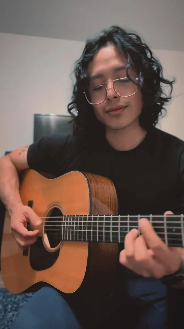 René Velarde playing an acoustic guitar at home